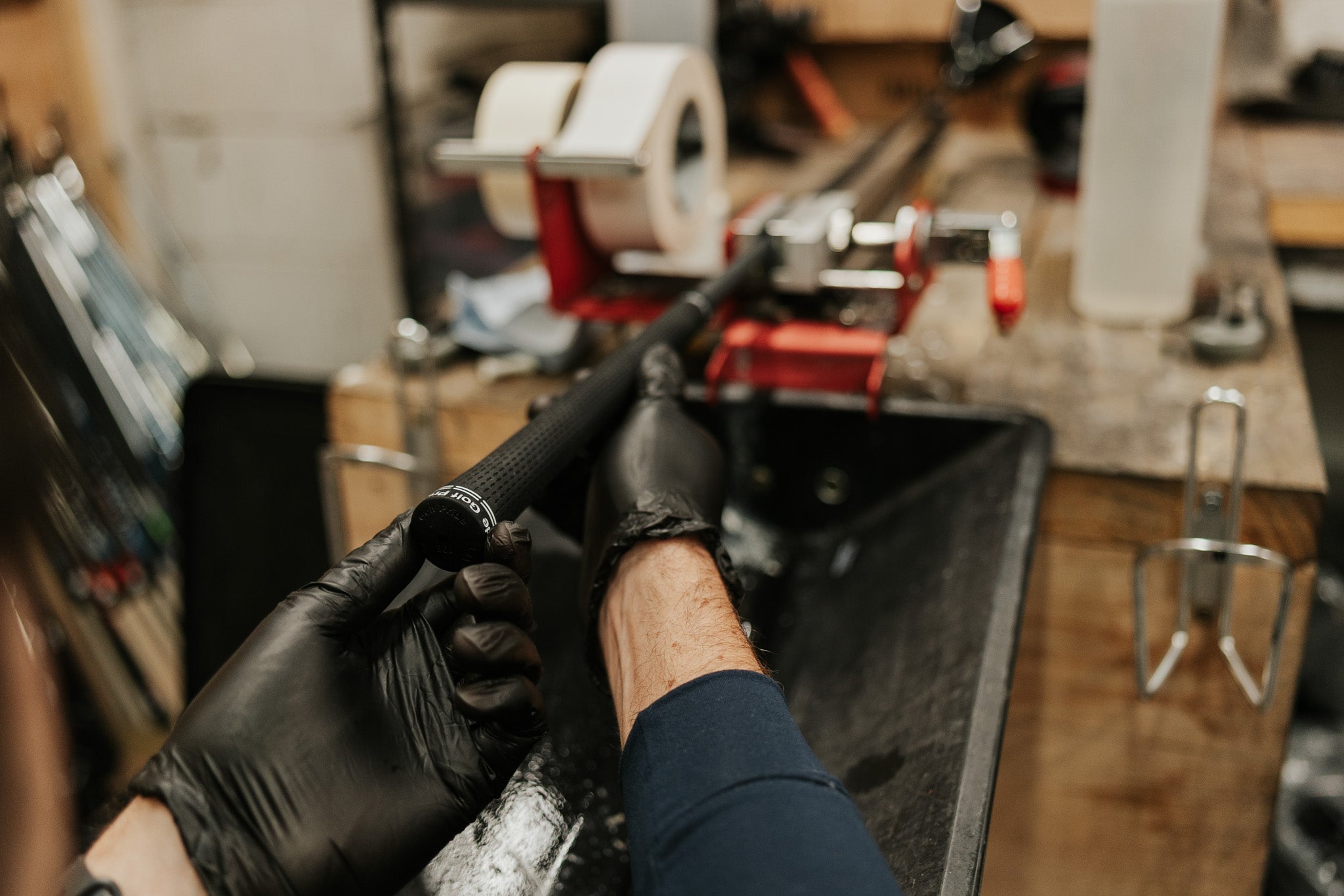 Person working on a golf club in a workshop setting